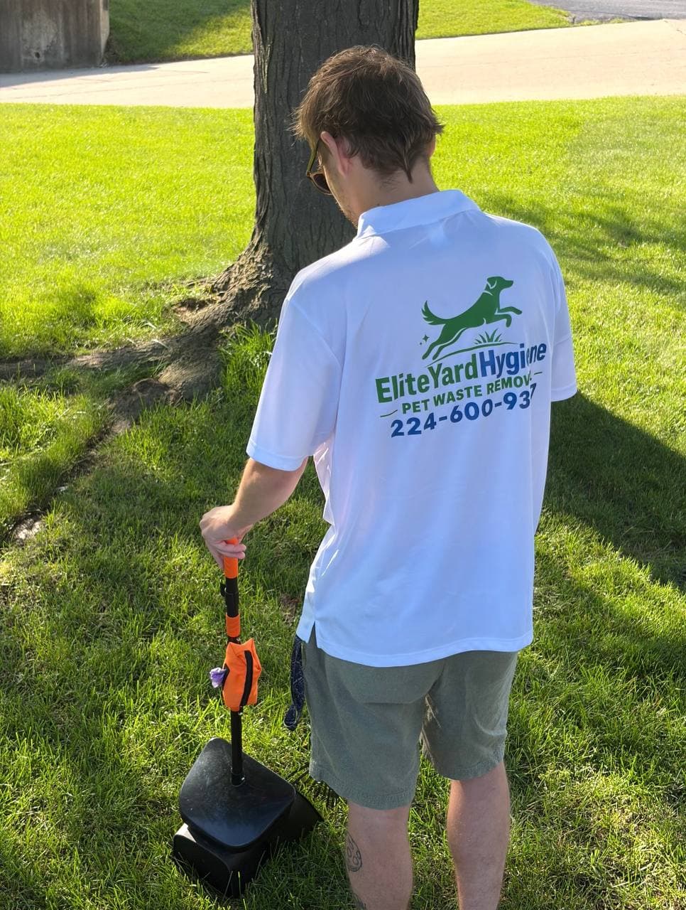 Elite Yard Hygiene pet waste removal service in action, with a professional using a pooper scooper to clean a yard